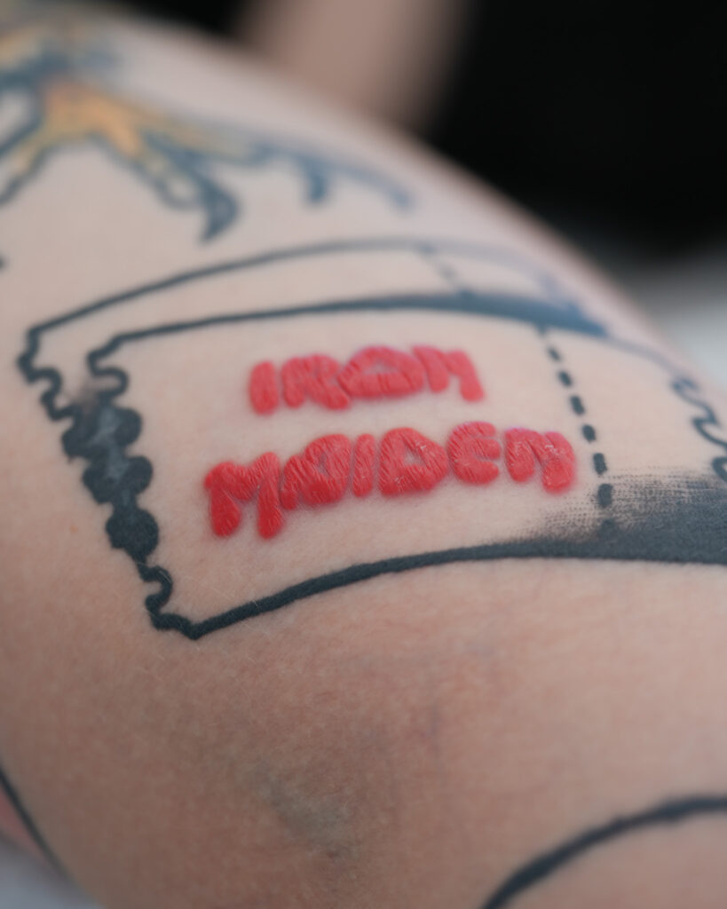 Tatuaż z czerwonym napisem „Iron Maiden”.
